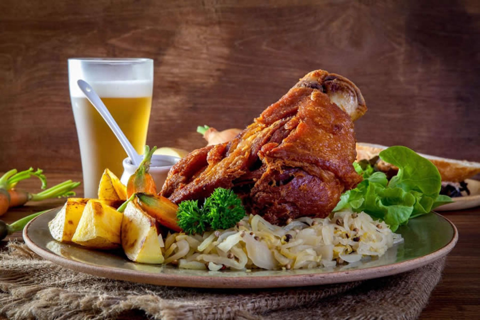 Pratos típicos de Blumenau com linguiças, chucrute e pães variados em uma mesa de madeira ao ar livre, complementados por uma caneca de cerveja escura.